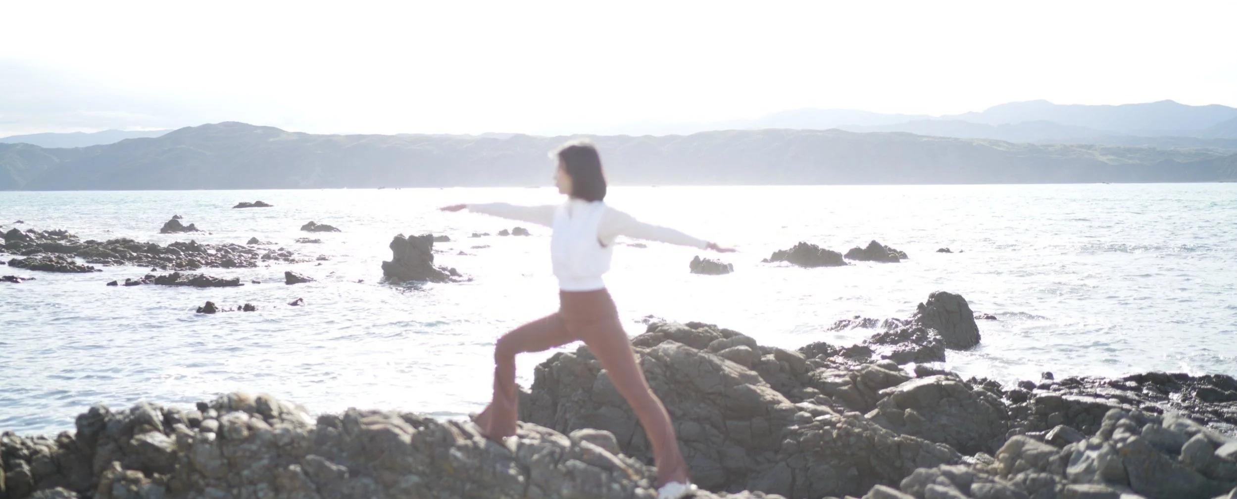 Lynn Tiang, yoga pose on rocks overlooking the ocean