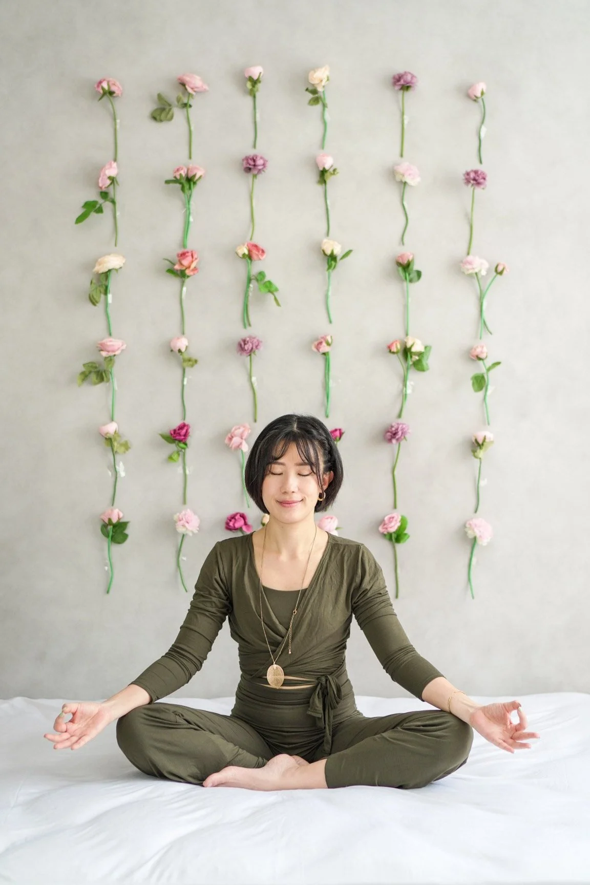 Lynn Tiang meditating against a floral wall